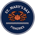 A circular logo with a navy blue background, white rope border, and the text "St. Mary's Bay Fisheries" in white. At the center, there's an illustration of an orange crab above a wavy, white line, representing water.